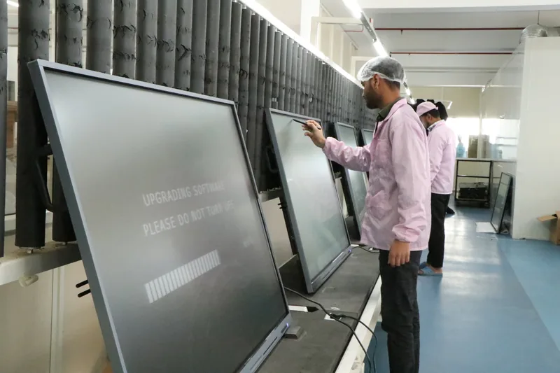 A technician checking interactive panels running a software upgrade on the testing line
